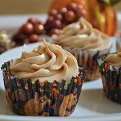 three cupcakes with frosting sitting on a plate next to other dessert items