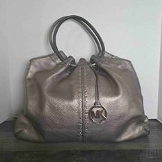 Like New Michael Kors Metallic Pewter Double Handle Logo Charm Handbag Size Extra Large This Michael Kors Tote Is A Stunning Accessory, Featuring A Pebbled Leather Exterior In Metallic Pewter And Accented With A Tasteful Logo Charm. The Double Handles Make For Comfortable Carrying, And Its Spacious Interior Can Hold All Your Essentials. Whether You're Heading To The Office, Shopping, Or Out For The Evening, This Handbag Is Sure To Make A Statement. Size: Womens Extra Large Condition: Like New Co Tote Handbag, Michael Kors Bag, Fashion Handbags, Pebbled Leather, Tote Handbags, Extra Large, Handles, Michael Kors, Bag Lady