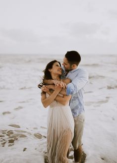 a man and woman hugging on the beach