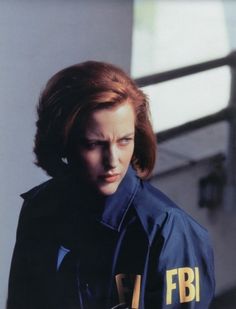 a woman with red hair wearing a blue jacket and looking at something in her hand