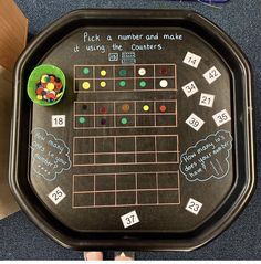 a child's hand holding a black tray with numbers and counters on it