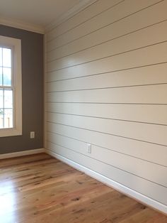 empty room with hard wood flooring and white painted shiplap on the wall