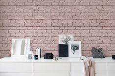 pink brick wallpaper in a bedroom with white dresser and sideboard, framed pictures on it