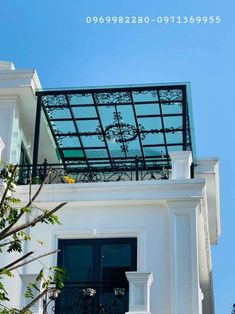 the top of a white building with a glass roof and wrought iron balcony railings