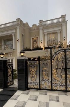 an ornate gate in front of a large house with two balconies on the second floor