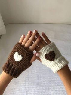 two hands wearing knitted gloves with hearts on them