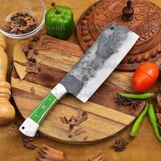 a large knife sitting on top of a wooden cutting board next to vegetables and spices