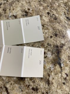 three different shades of white paint sitting on top of a marble countertop next to each other