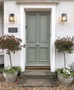 the front door of a white house with potted plants on either side and a sign that says thank you, its & b pigeon it's written in the caption