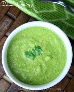 a white bowl filled with green soup on top of a wooden table