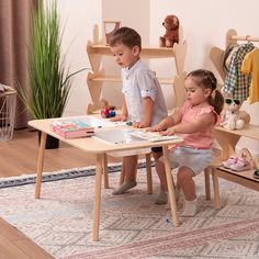 two children sitting at a wooden table playing with blocks and toys in a playroom