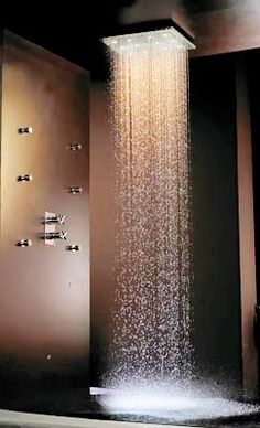 a shower head with water running from it's sides in a dark bathroom area