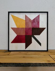 a wooden frame with an abstract design on the wall next to a wood table top