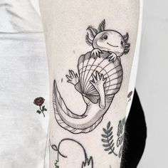 a woman with a tattoo on her arm holding a lizard in the shape of a fish