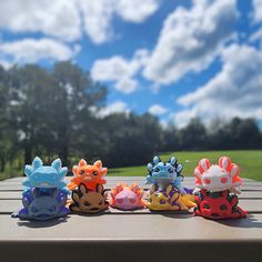 five small toy animals sitting on top of a wooden table in front of some trees