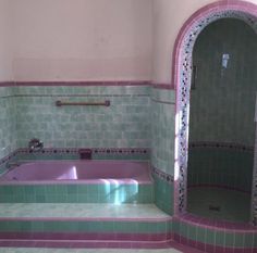 a bathroom with pink and green tiles on the walls, purple bathtub in between two arched doorways