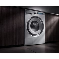 a front loading washer sitting on top of a tile floor next to a wooden wall