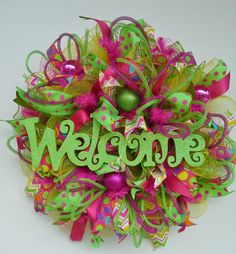 a green and pink wreath with the word welcome