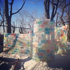 there are many ice blocks on the ground in front of some trees and fenced in area