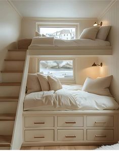 two bunk beds with white linens and pillows in a small room next to a window