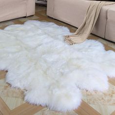 a white sheepskin rug is on the floor in front of a beige couch and chair