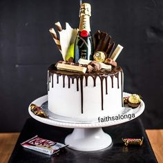 a white cake with chocolate drizzled on top and champagne bottle next to it