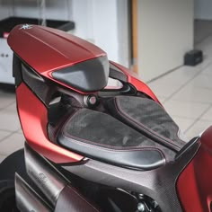 a red and black motorcycle parked in a garage next to a white tile flooring