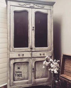 an old wooden cabinet sitting next to a vase filled with flowers