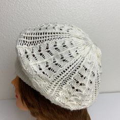 a white knitted hat on top of a mannequin's head in front of a wall