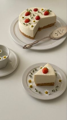 two slices of cheesecake with strawberries and daisies on the plate next to each other