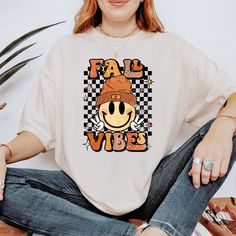 *If you would like a colour or size that is not listed, please contact us. Embrace the cozy autumn season with our Fall Vibes Shirt, designed to bring warmth and style to your wardrobe. Perfect for pumpkin spice lovers and fall enthusiasts. 🍂 Soft and Comfortable: Made from high-quality cotton for a cozy feel, ideal for layering on chilly days. 🎃 Cute Fall Design: Features a retro-inspired graphic that celebrates the beauty of fall, from pumpkins to autumn leaves. 🍁 Versatile Style: Perfect f Retro Fall Tops For Fan Merchandise, White Fall Fan Merchandise T-shirt, Sublimation Print T-shirt For Fall Streetwear, White Fan Merchandise T-shirt For Fall, Retro Fan Merchandise Tops For Fall, Fall Graphic Tee Fan Merchandise Tops, Fall Fan Apparel T-shirt With Graphic Print, Fan Apparel Graphic T-shirt For Fall, Fan Apparel Graphic Print T-shirt For Fall