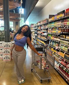 a woman standing next to a shopping cart in a grocery store