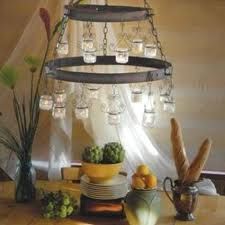 a chandelier hanging from the ceiling with mason jars and fruit in front of it