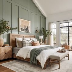 a bedroom with green walls and white bedding in the center is a large window