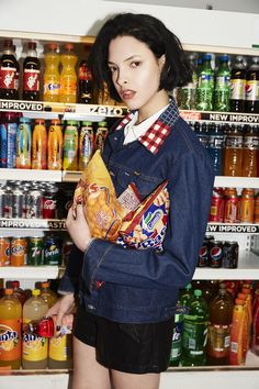 a woman standing in front of a shelf full of sodas