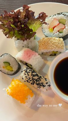 sushi on a white plate with sauce and lettuce next to it,