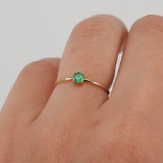 a woman's hand with a gold ring and green stone on the middle finger