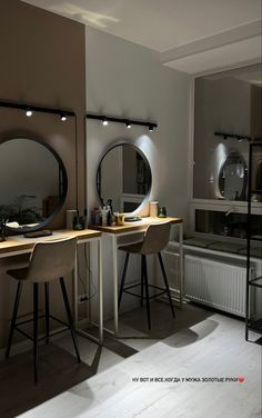 a room with two mirrors and stools in it