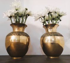 two gold vases with white flowers in them