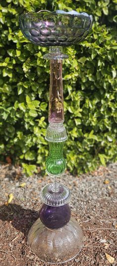 three glass candlesticks sitting on top of each other in front of some bushes