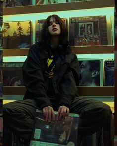 a man sitting on top of a wooden bench next to a wall covered in posters