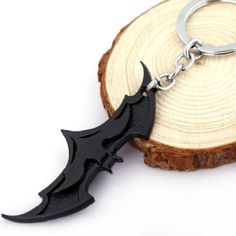 a black bat shaped keychain sitting on top of a piece of wood