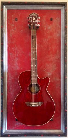 a red guitar hanging in a frame