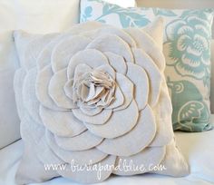 a white pillow with a large flower on the front and back of it, sitting on a couch