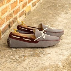 a pair of gray and brown shoes sitting on the ground next to a brick wall