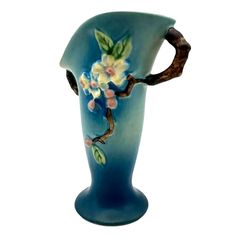 a blue vase with flowers painted on the front and sides, sitting against a white background