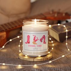 a candle that is sitting on a table next to some string lights and a guitar