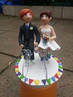 a wedding cake topper with a bride and groom on the bike handlebars