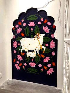 a cow painted on the side of a wall with pink flowers and leaves around it