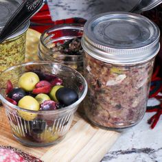 jars filled with food sitting on top of a wooden cutting board next to other foods